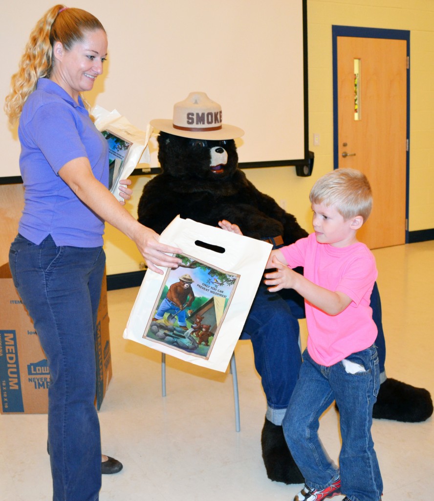 The Delaware Forest Service's  Ashley Peebles hands a Smokey gift bag of school supplies to kindergarten student Paul Bonavita after he pledges to Smokey Bear that he will never play with matches.  He was one of an estimated 535 kindergarten students who participated in the fire prevention program at McIlvaine Early Childhood Center in Magnolia, the largest program in the First State.