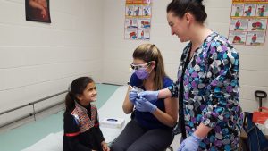 East Millsboro Elementary Student Hajra Sultan smiles during her visit with Registered Dental Hygienist Ashley Hudson and school nurse Erica Jester.