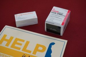 Two boxes of Naloxone above the Help Is Here sign