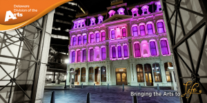The Grand Opera House, a historic opera house in Wilmington, DE, with its exterior lit up in purple lights at night time