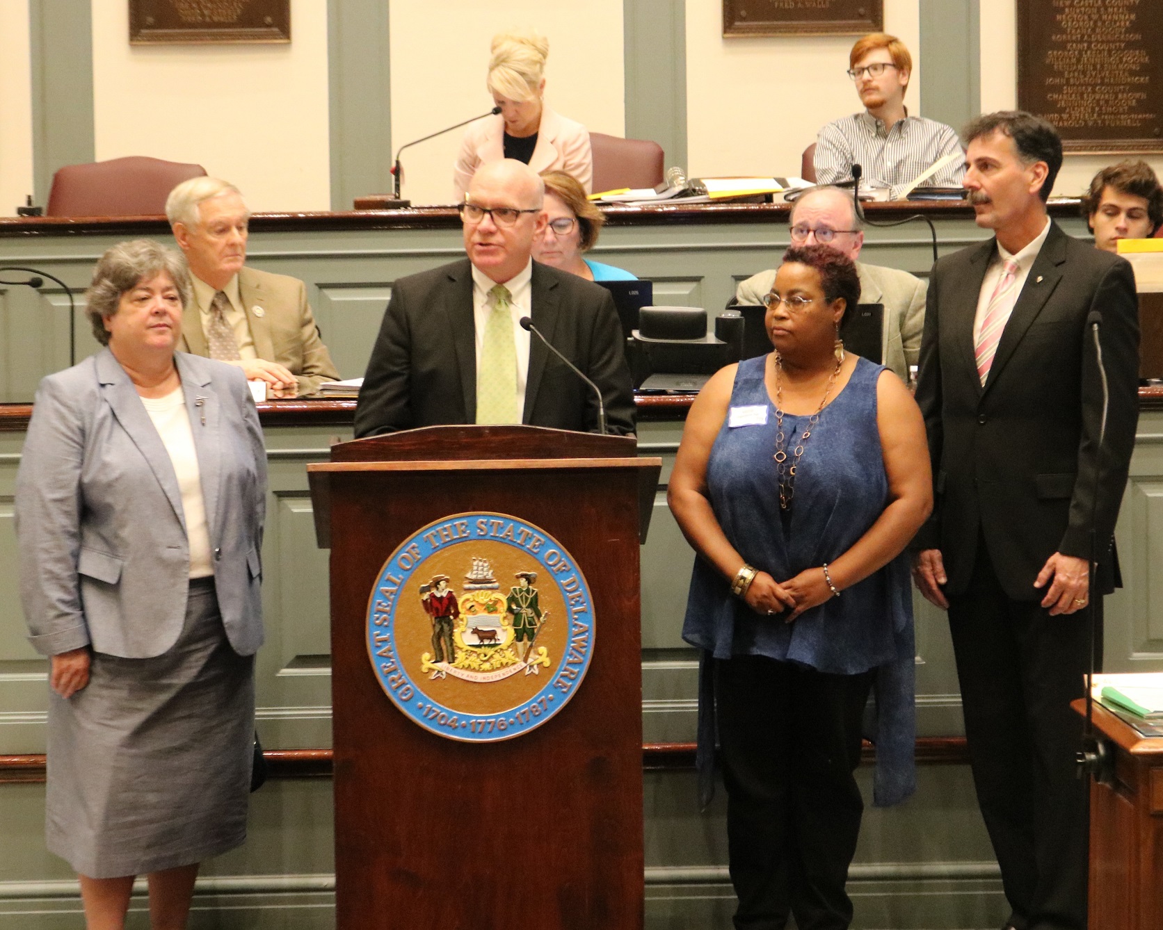 Division of Historical and Cultural Affairs Director Tim Slavin (at podium) speaking before the Delaware Senate passed Concurrent Resolution 76 recognizing the division for achieving accreditation by the American Alliance of Museums. From left foreground are division Deputy Director Suzanne Savery; Slavin; Gloria Henry, site supervisor of the John Dickinson Plantation; and Edward McWilliams, manager of the division’s Collections, Affiliates, Research and Exhibits Team.