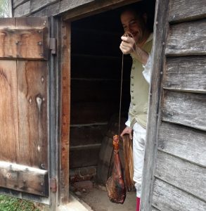 Historic-site interpreter Chris Merrill demonstrating the curing of meat in the plantation’s smokehouse.