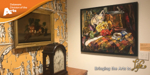 Delaware Division of the Arts on an orange banner over a photo of where two walls meet in the corner. One wall is white with a painting hanging on it, and the other wall is covered in decorative, yellow wallpaper with a painting hanging on it and an antique, wooden desk clock sitting in front of it on a desk