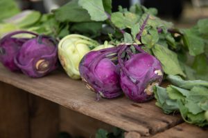 purple and green kohlrabi bulbs on wood crates at farmers' market 