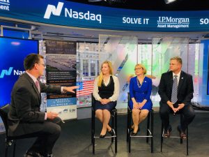 Seated under a Nasdaq banner are State Treasurer Colleen Davis, Carla Sydney Stone, and Dave Harriss. They are being interviewed by Rob Phillips