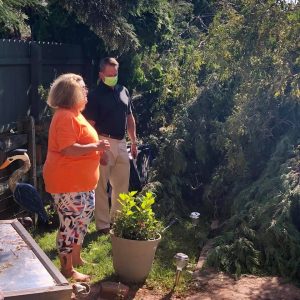 Insurance Commissioner Trinidad Navarro talks with a resident next to a down tree.