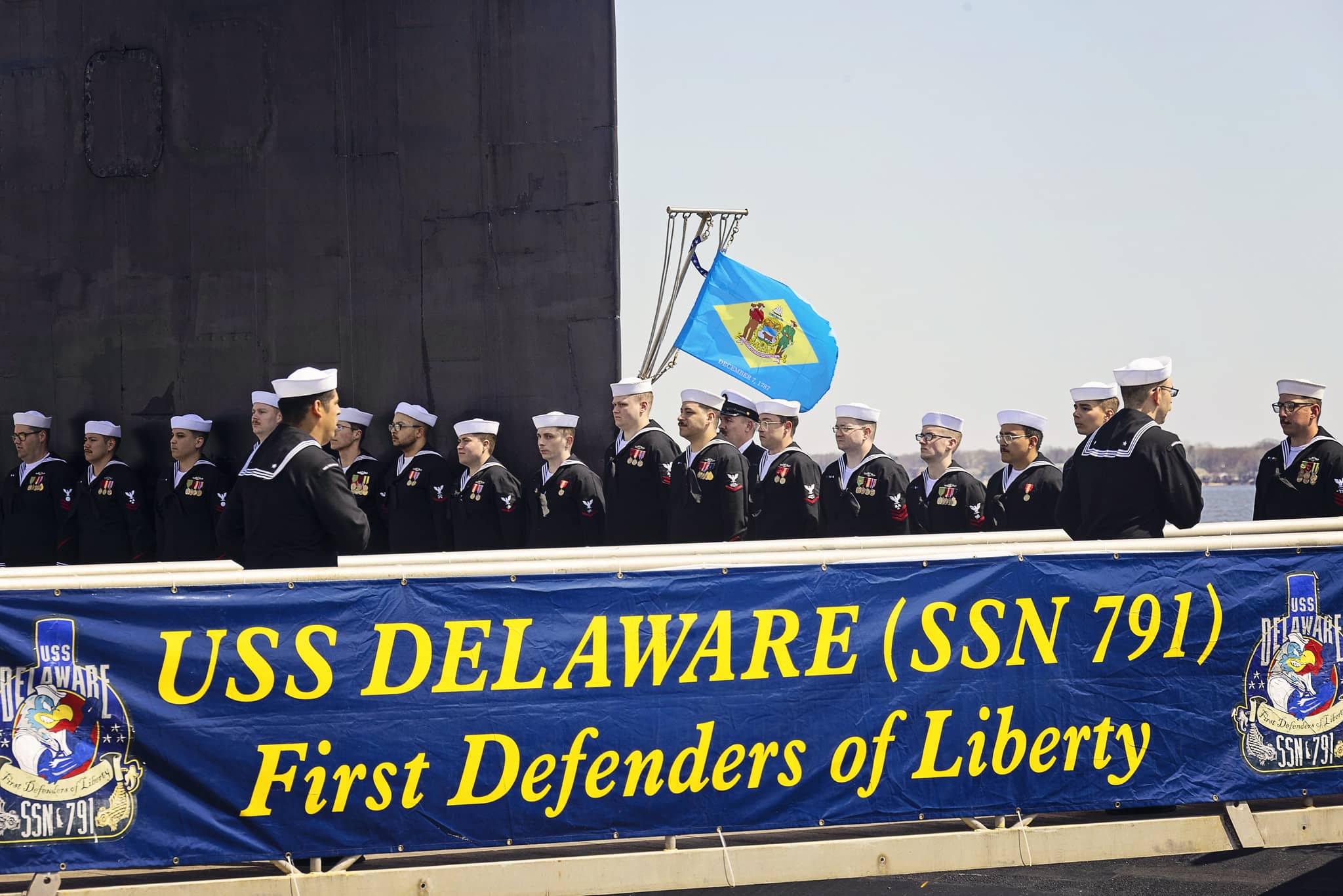 Members of the USS Delaware stand on the submarine during the Ceremonial Commissioning Ceremony