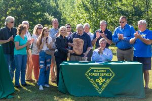 Governor Carney seated at table with Senator Ennis' family after signing Bill 328 at Blackbird State Forest