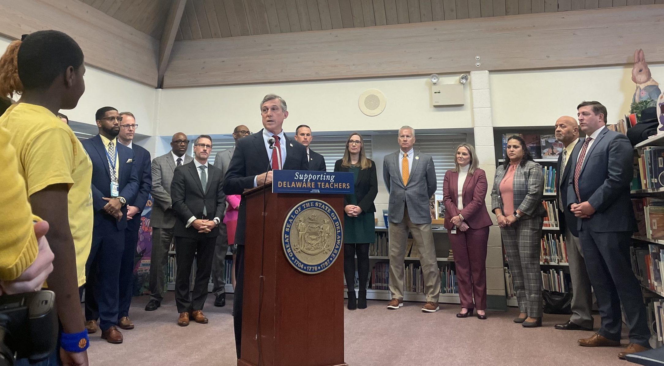 Governor Carney stands behind a podium in front of school administrators, advocates, and members of the General Assembly