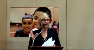 Bethany Hall-Long delivers remarks in front of a photo of school age children.