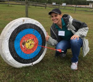 Delaware Becoming an Outdoors Woman participant standing beside a bullseye.
