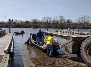 Three volunteers remove the trash collected during the cleanup from a boat.