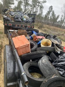 A pickup truck with an attached trailer full of trash and discarded tires