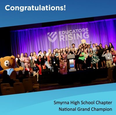 A group of students stands smiling for the camera. The top of the picture says, "Congratulations." The bottom of the picture says, "Smyrna High School Chapter National Grand Champion."