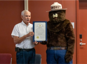 Secretary of Agriculture Michael T. Scuse presents a proclamation to Smokey Bear in honor of his 80th birthday at the Dover Public Library.