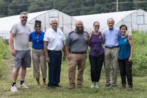 Pictured L to R with two high tunnels and sunflowers at Dittmar Family Farm: Doug (farm intern), Nikko Brady, Delaware Council on Farm & Food Policy, Secretary of Agriculture Michael T. Scuse, Zach and Jenny Dittmar, Senator Tom Carper, and Maddie (farm staff).