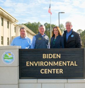 officials and dignitaries standing behind the Biden Environmental Center sign