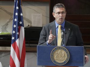 Governor Meyer stands at a podium with the state seal on the front and an American flag in the background.