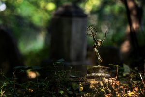 The Emmy award sits in the foreground, with a headstone, trees and grass in the Mt. Olive Cemetery in the background.