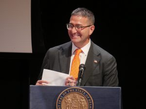 Governor Matt Meyer stands at a podium smiling.