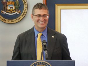 Governor Matt Meyer stands in front of a podium.