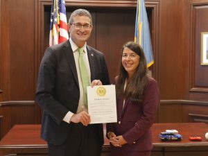 Governor Matt Meyer holds an official proclamation and stands to the left of new DHSS Secretary Christen Linke Young after her swearing in.