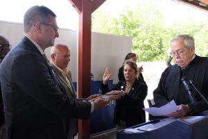 Governor Meyer is to the left, holding a bible in front of Brig. Gen. Karen Berry, who has her hand on the bible and her right hand raised as a judge to her right performs the swearing in. 