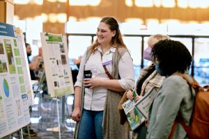 Three attendees at the 10th Delaware Wetlands Conference discuss the poster presentations in front of one poster.
