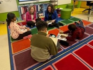 Delaware Lt. Governor Gay and Education Secretary Marten sit on the floor as they read to students.