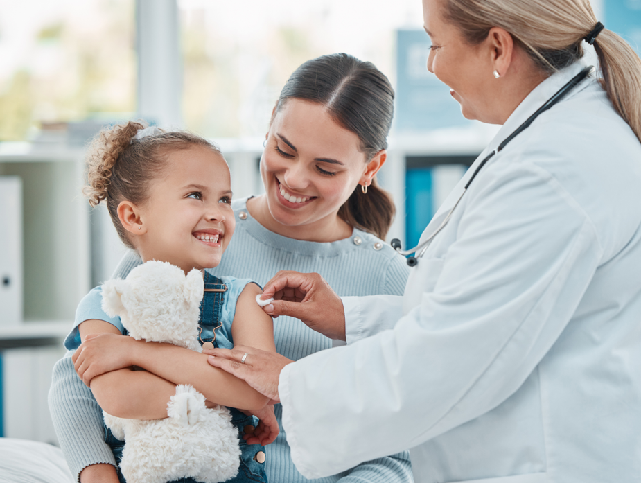A doctor using a cotton ball on a little girl's arm while administering an injection in a clinic