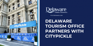 Half the screen features an image of City Hall in Philly, the other half has the DE Tourism Office logo on a dark blue background.