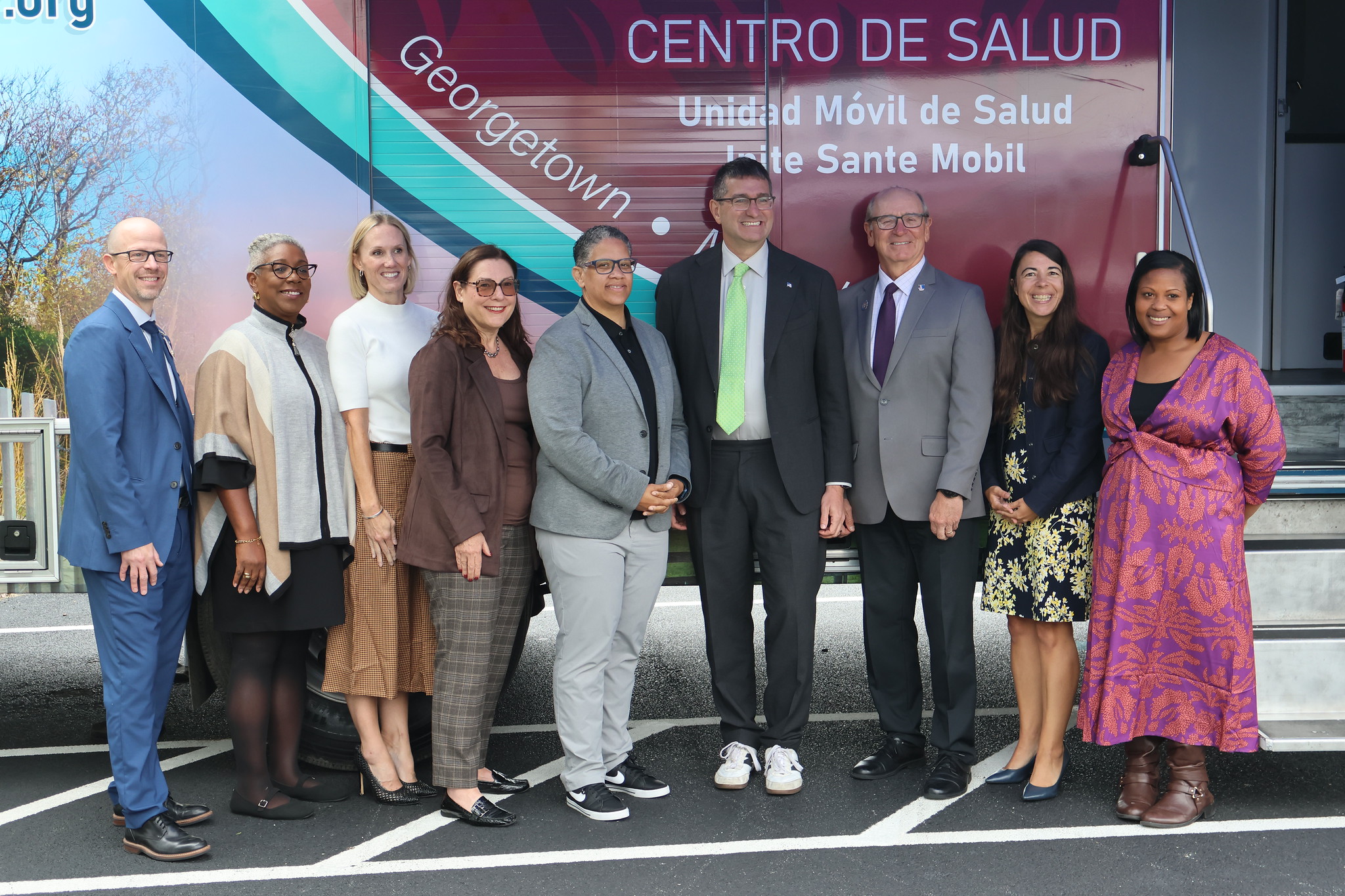 A group of leaders pose outside of a mobile health unit.