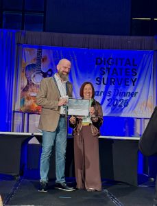 On stage, Jerry Whisman accepts award from Teri Takai.